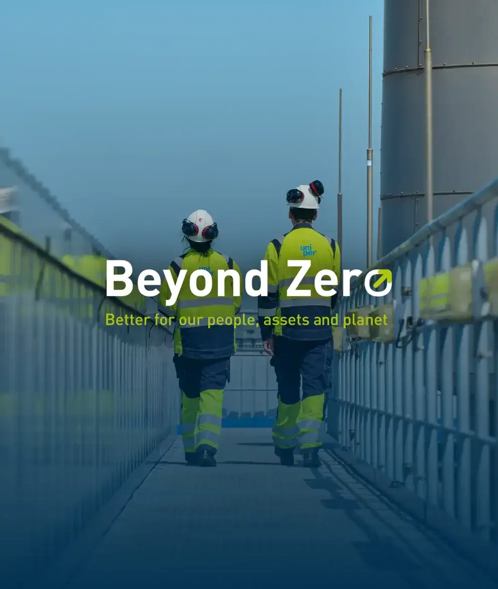 Two Uniper employees in high-visibility safety clothing walking on an industrial walkway, with the text ‘Beyond Zero – Better for our people, assets and planet’