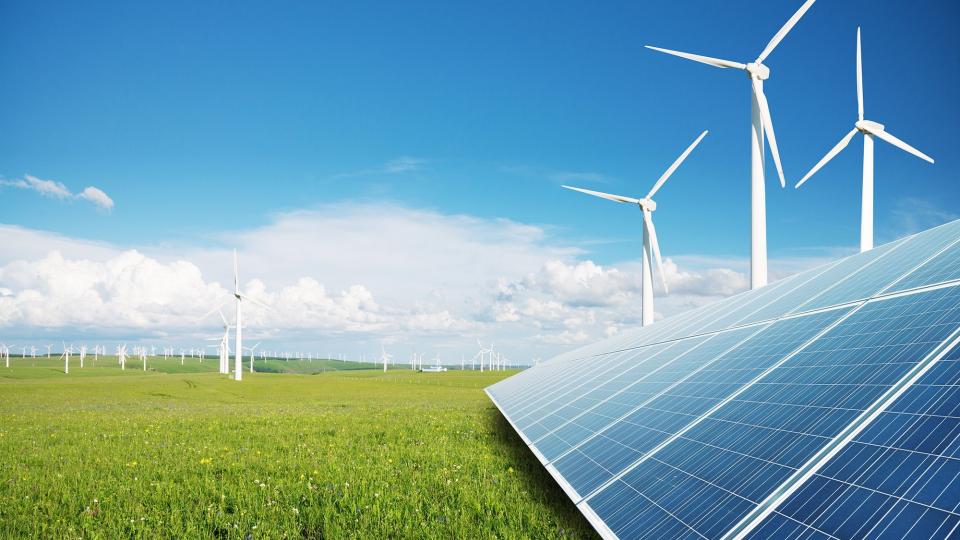 Image of solar panels in the foreground and wind turbines in the background