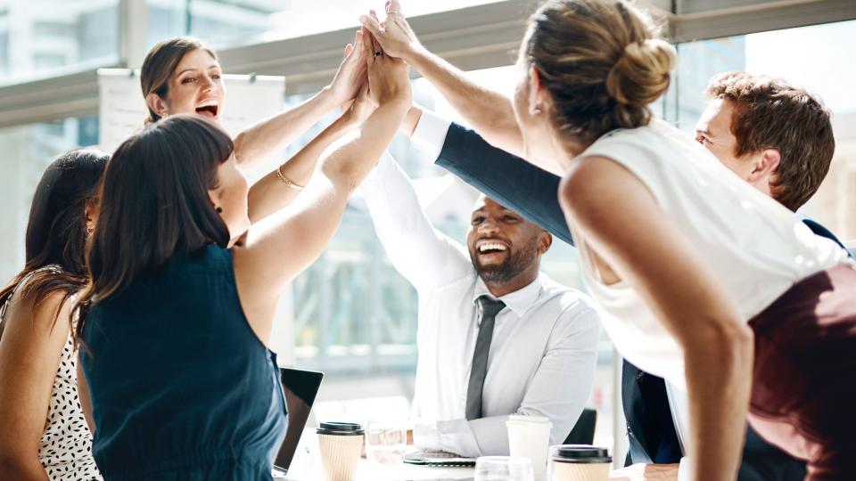 Stock image of colleagues giving a high five in the office