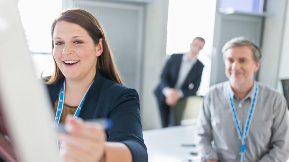 Female Uniper employee standing at a flipchart in a meeting room, two other male employees can be seen in the background