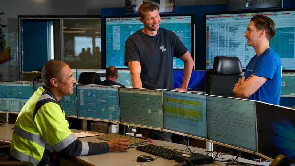 Uniper team members in the control room discussing operations in front of multiple monitoring screens.