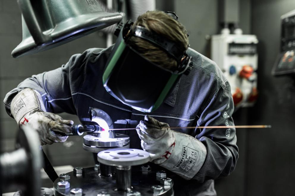 Technischer Auszubildender mit Schweißmaske beim Schweissen in der Werkstatt