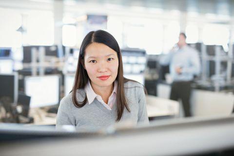 Mitarbeiterin auf dem Tradingfloor vor vielen Bildschirmen